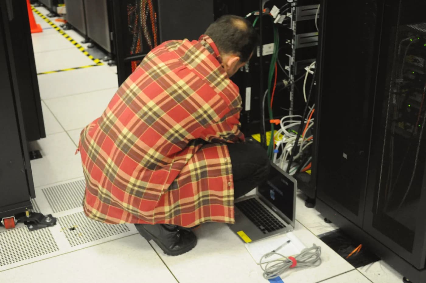 A technician using a laptop beside server racks at NERSC