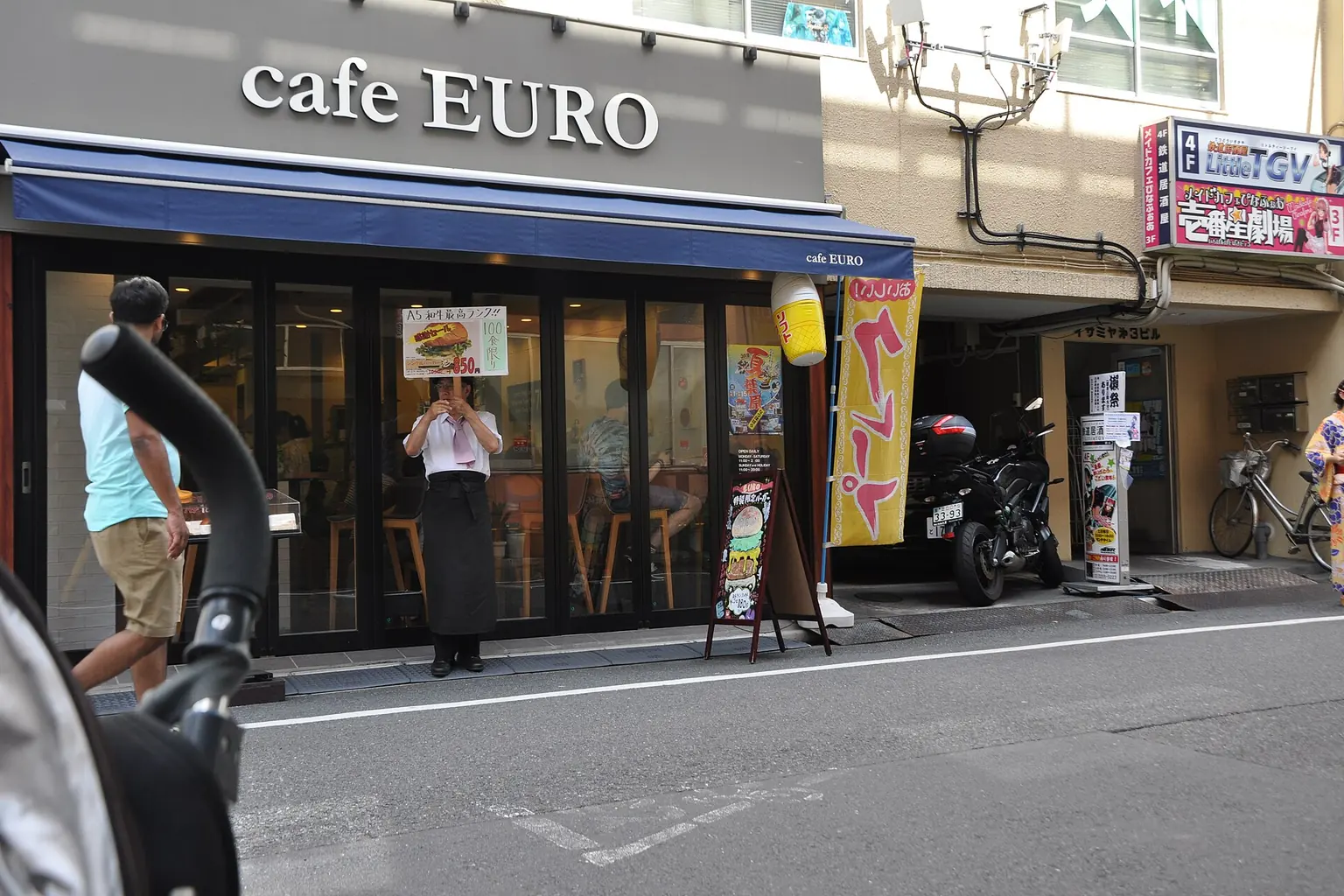 A cafe employee standing outside with a menu board