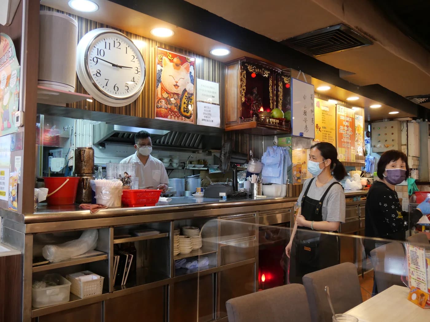 A chef and serving staff in an open restaurant kitchen