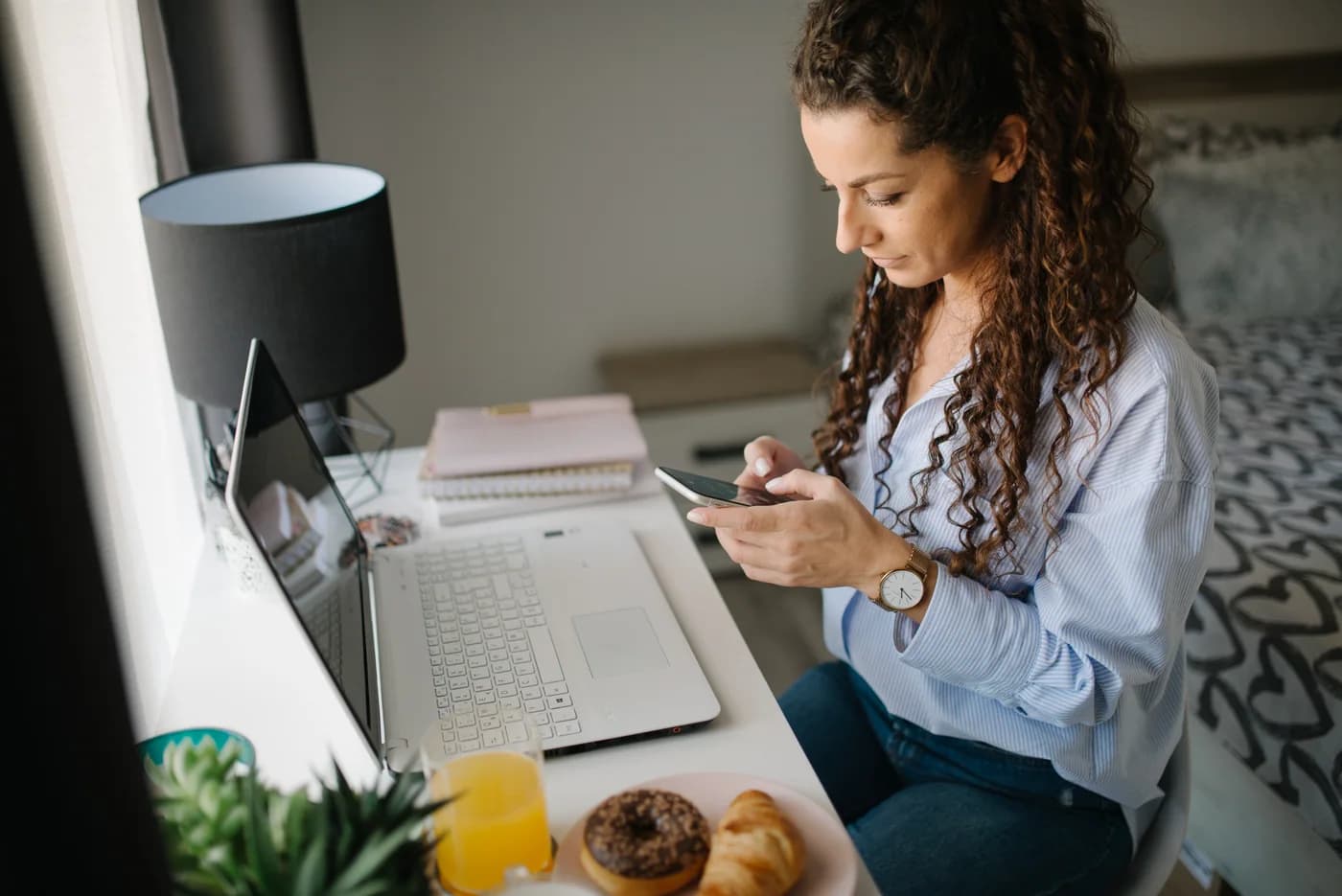 A person using a smartphone at a home workspace