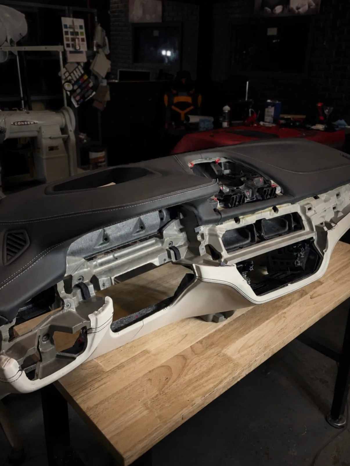 BMW X5 dashboard component on an upholstery workbench at Motenza Auto Couture